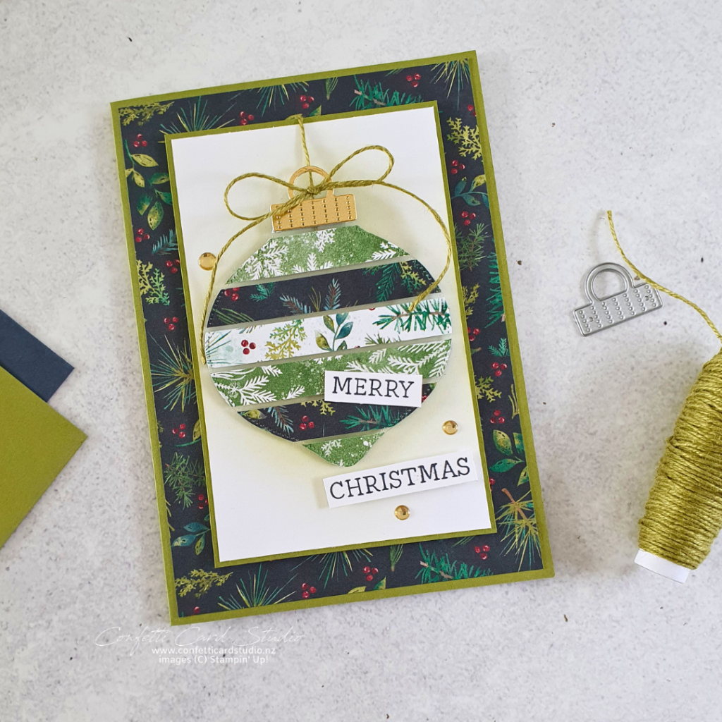 Handmade floating strips Christmas card with a bauble made from strips of Christmas paper on a layer of window sheet. The colours are green and gold with a hit of red..