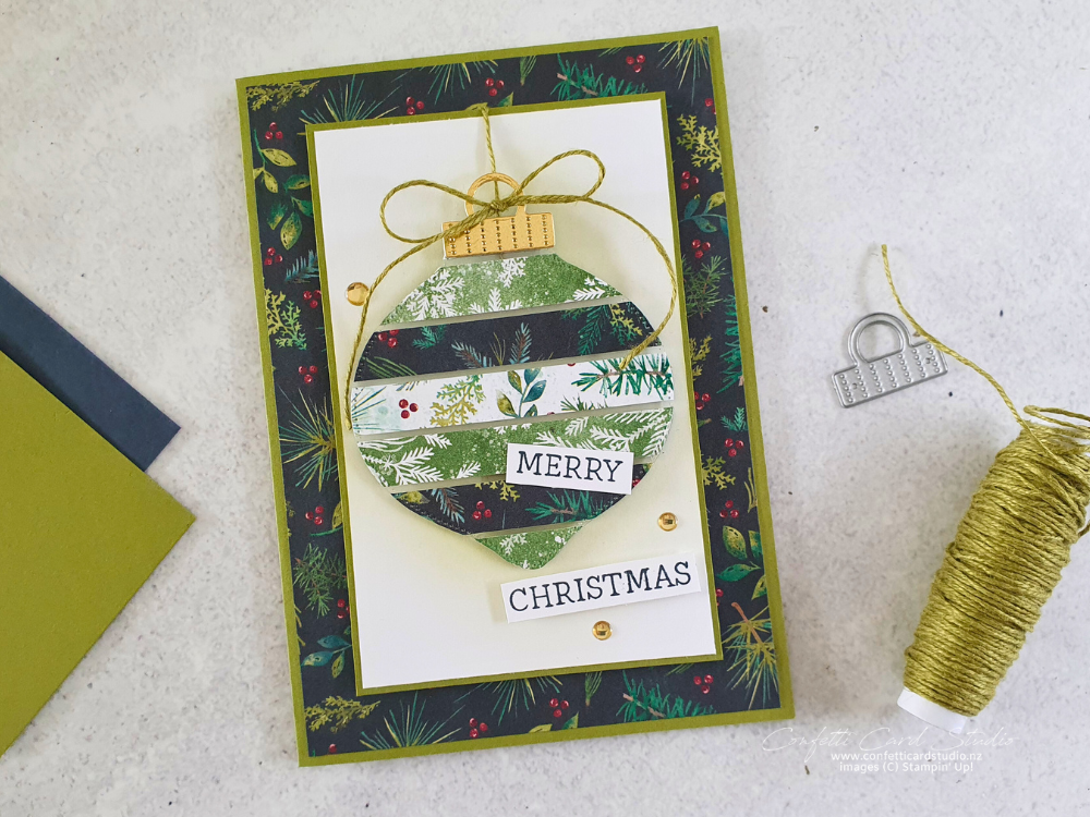 Handmade floating strips Christmas card with a bauble made from strips of Christmas paper on a layer of window sheet. The colours are green and gold with a hit of red..