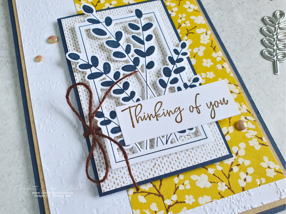 Handmade card in Blue, Yellow white and natural. Features leaves in a cut away frame and the sentiment Thinking of You.